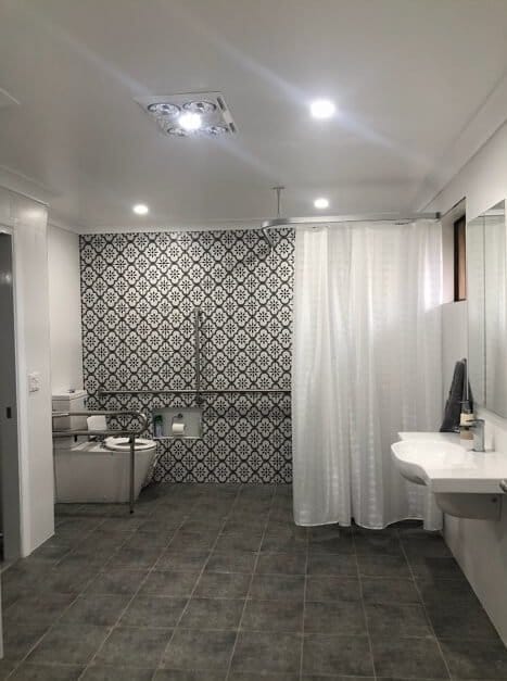 An accessible bathroom with a toilet, shower and sink.
